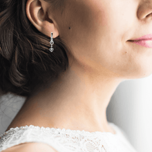 Load image into Gallery viewer, model showcasing  Dangling Rhodium Heart Earrings 